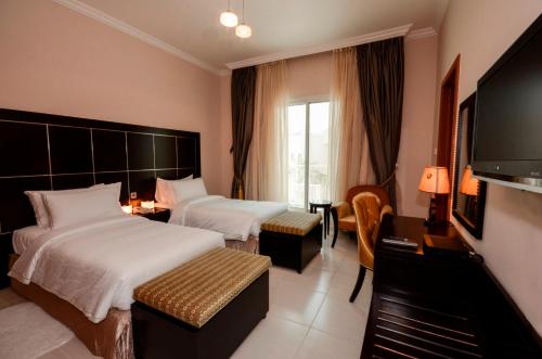 Habitación de hotel con 2 camas y TV de pantalla plana. en Coral Boutique Villas, en Dubái