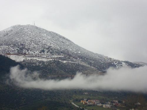a mountain covered in snow and clouds in the valley at Stalaktites in Ioannina