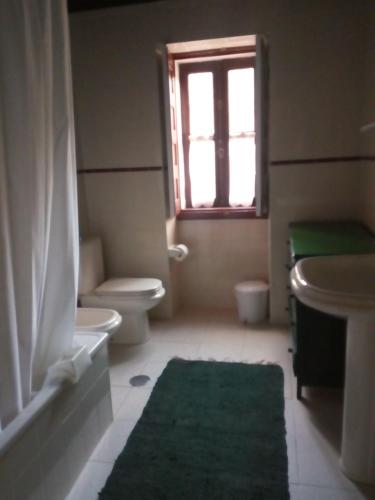 a bathroom with a toilet and a sink and a window at Casa da Sicó in Manteigas