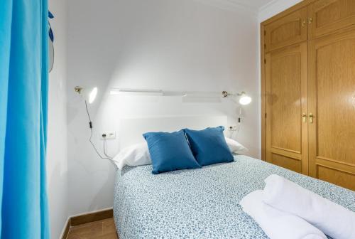 um quarto com uma cama com almofadas azuis em Nordik Apartments Village - La Cala "Raseborg" em Cala del Moral