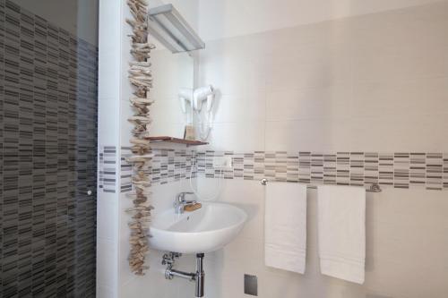 a white bathroom with a sink and towels at AFFITTACAMERE VIA DEI MILLE in La Spezia