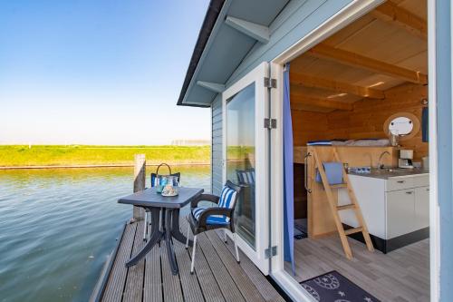 een terras met een tafel en stoelen op een boot bij Waterlodge in Wilhelminadorp