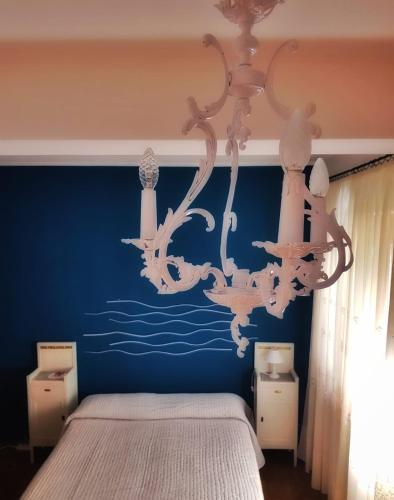 a bedroom with a blue wall with a chandelier at Dimora Damare in Caronia Marina
