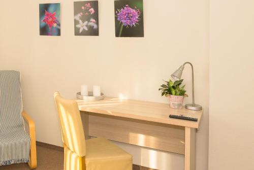 a desk with a chair and a lamp and pictures on the wall at Old Tree Villa & Restaurant in Oświęcim