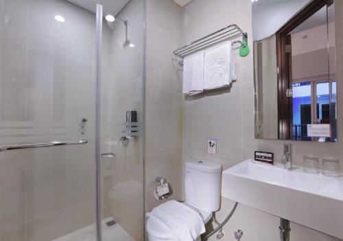 a bathroom with a shower and a toilet and a sink at Fame Hotel Sunset Road in Kuta