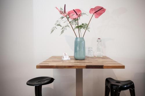 a table with a blue vase with flowers on it at Kuwadro Guesthouse Centrum in Amsterdam