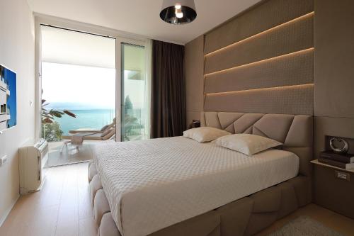 a bedroom with a large bed and a large window at Opatija Deluxe Apartment with swimming pool in Opatija