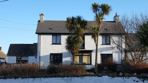 a white house with palm trees in front of it at Dunseverick Ramblers Rest in Bushmills