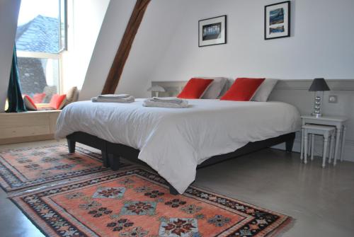 um quarto com uma cama grande com almofadas vermelhas e um tapete em Natangora em Marcillac-Vallon