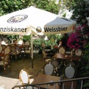 an outdoor restaurant with an umbrella and tables and chairs at Weingasthaus zum Fährhof in Winningen