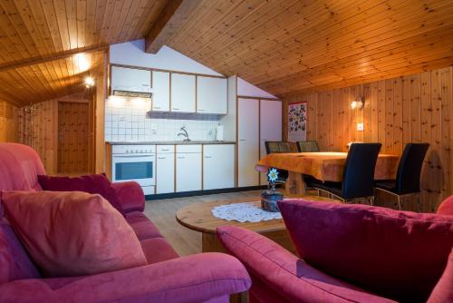 eine Küche und ein Esszimmer mit rosa Stühlen und einem Tisch in der Unterkunft Apartments Orphelja in Saas-Grund