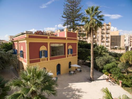 a yellow and orange building with a palm tree at Giardini Mon Plaisir in Trapani