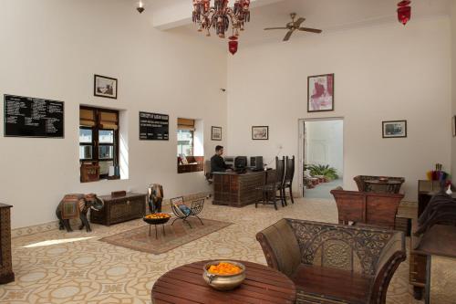 a living room with chairs and tables and a man in the background at Aaram Baagh Pushkar by Pachar Group in Pushkar