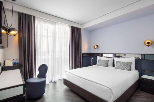 The Westist Hotel & Spa - Special Category في إسطنبول: غرفة نوم بسرير ابيض كبير وكرسي