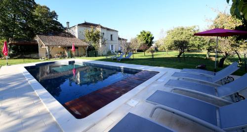 a swimming pool with white chairs next to a house at Belle demeure familiale avec piscine proche St Emilion in Bossugan