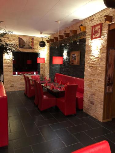 comedor con sillas rojas y mesa en Eiscafé - Pizzeria Antonio, en Lichtenau