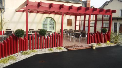 une clôture rouge devant une maison avec une table dans l'établissement Beauséjour, à Sainte-Suzanne