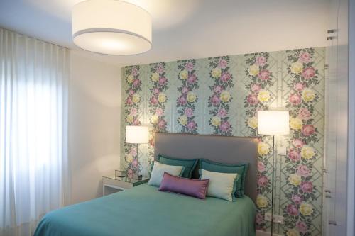 Un dormitorio con una cama azul con papel pintado floral. en Casa do Ácer, en São Vicente Ferreira
