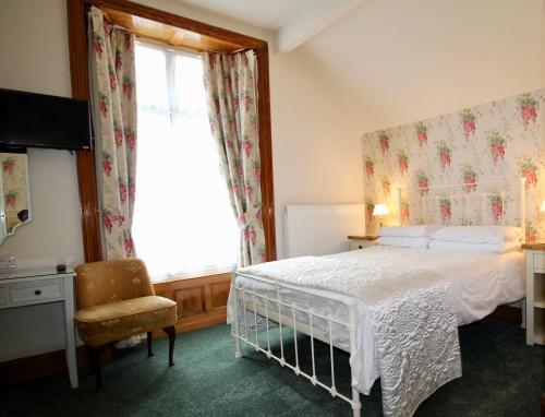 ein Schlafzimmer mit einem Bett, einem Fenster und einem Stuhl in der Unterkunft The Haven in Windermere