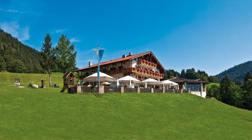 a large building with umbrellas on a green hill at Hotel-Gasthof Nutzkaser in Ramsau