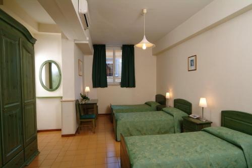Pokój hotelowy z 2 zielonymi łóżkami i lustrem w obiekcie Casa Di Santa Francesca Romana a Ponte Rotto w Rzymie