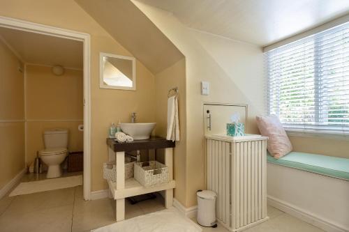 a bathroom with a sink and a toilet and a window at Little House Villa in Cape Town