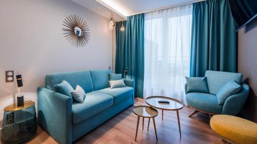 a living room with a blue couch and two chairs at voco Strasbourg Centre - The Garden by IHG in Strasbourg