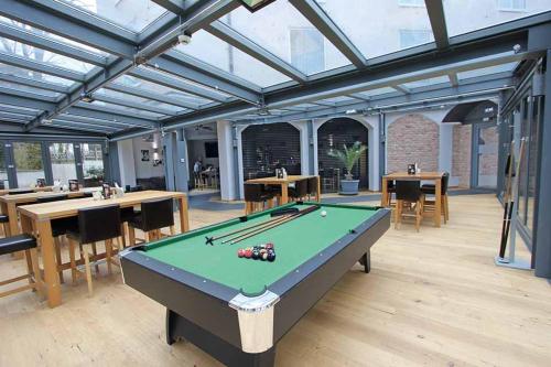 a pool table in a room with tables and chairs at SOLEWERK Hotel in Bad Salzungen