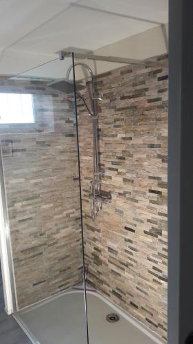 a glass shower in a bathroom with a brick wall at Taillefer in Saint Paul de Loubressac