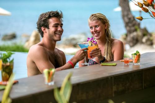 Ein Mann und eine Frau sitzen mit einem Drink an einem Tisch. in der Unterkunft Sea Dance Resort in Strand Choeng Mon