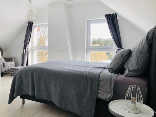 een slaapkamer met een bed met een blauwe deken en een tafel bij Ferienhaus Eifel Charlotte in Dahlem