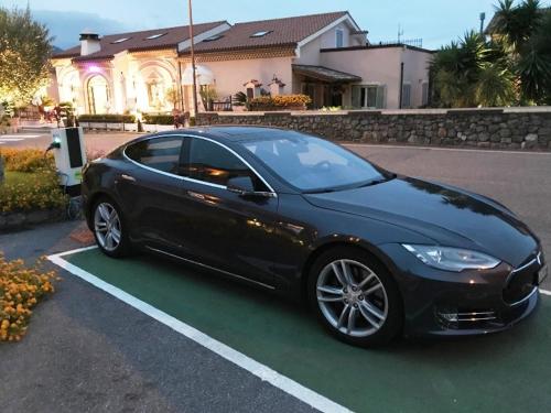 a black tesla parked in a parking lot at Hotel Ristorante Borgo La Tana in Maratea