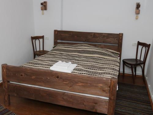 a bedroom with a wooden bed with two chairs at Casa Strabunicului in Pîrteştii de Sus
