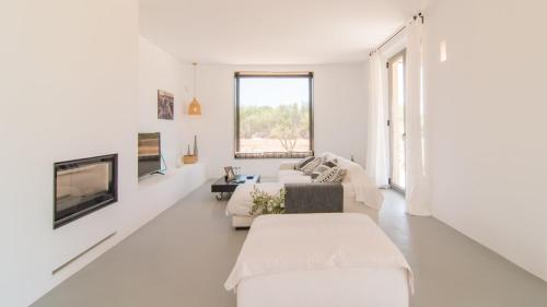a white living room with white furniture and a fireplace at Son Bennassar 2.0 in Felanitx