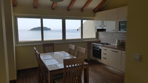 - une cuisine avec une table et une vue sur l'océan dans l'établissement Apartments Kvesic, à Prižba