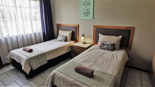 a bedroom with two beds and a chair in it at Hoogland Spa Resort Bela Bela in Bela-Bela
