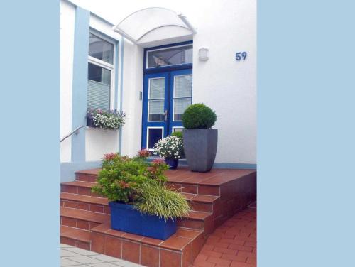 ein Haus mit einer blauen Tür und einigen Topfpflanzen in der Unterkunft Ferienhaus der kurzen Wege Objekt 40105 in Warnemünde