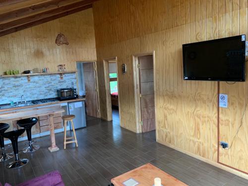 a living room with a tv on a wooden wall at Cabañas Cerro Huemules in Coihaique