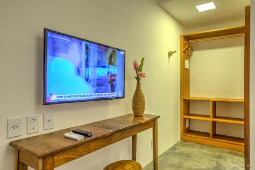 a television on a wall with a vase on a table at A Casa de Gabriella in Itacaré