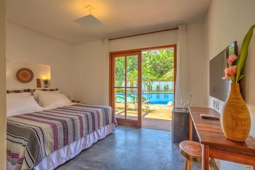 a bedroom with a bed and a table with a vase of flowers at A Casa de Gabriella in Itacaré