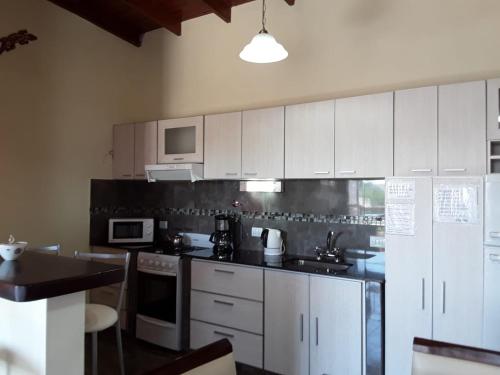 une cuisine avec des placards blancs et un comptoir noir dans l'établissement Arenas Calidas, à Las Grutas