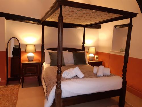 a bedroom with a canopy bed with white pillows at The Crown at Wells, Somerset in Wells