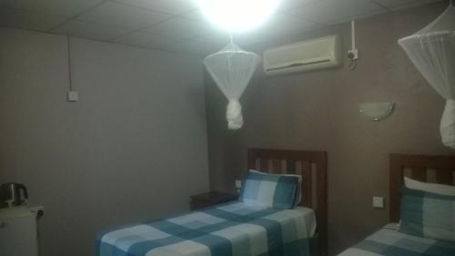 a room with two beds and a light on the ceiling at Gloria's Bed and Breakfast in Livingstone