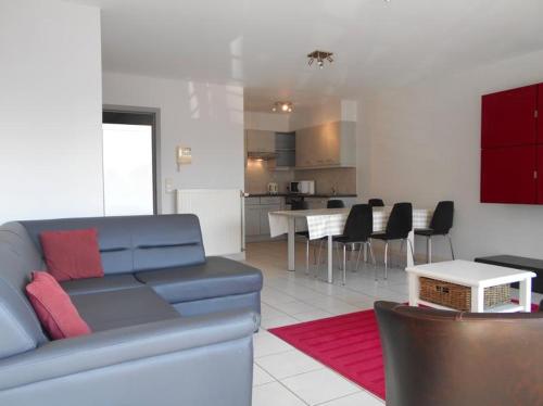 a living room with a blue couch and a kitchen at Residentie Kompas 102 in Nieuwpoort