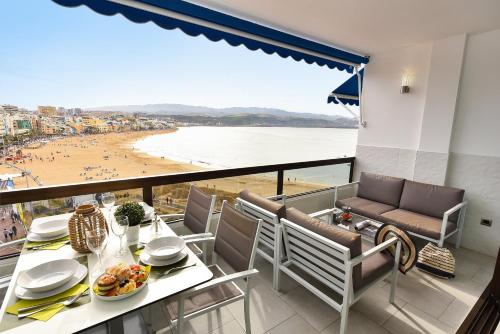 balcón con mesa y sillas y vistas a la playa en Apartamentos Don Carlos, en Las Palmas de Gran Canaria