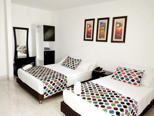 a bedroom with two beds and a couch at Hotel Cosmos Sincelejo in Sincelejo