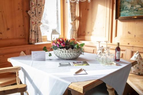 a table with a white table cloth and a bowl of flowers at Adolphine Garden in Rottach-Egern