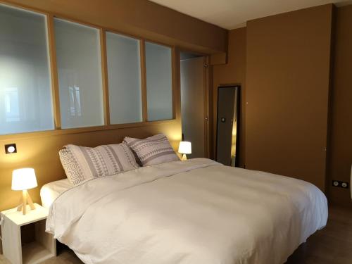 un grand lit blanc dans une pièce avec des fenêtres dans l'établissement Beautiful duplex in the center of Paris, à Paris