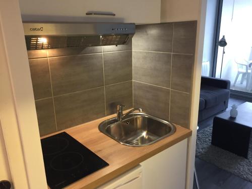 une cuisine avec un évier en acier inoxydable sur un comptoir dans l'établissement Plage des Minimes Résidence Clarines, à La Rochelle