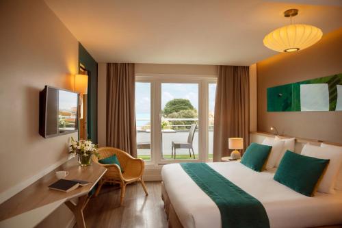 a hotel room with a bed and a desk and a window at Hôtel Le B d'Arcachon by Inwood Hotels in Arcachon